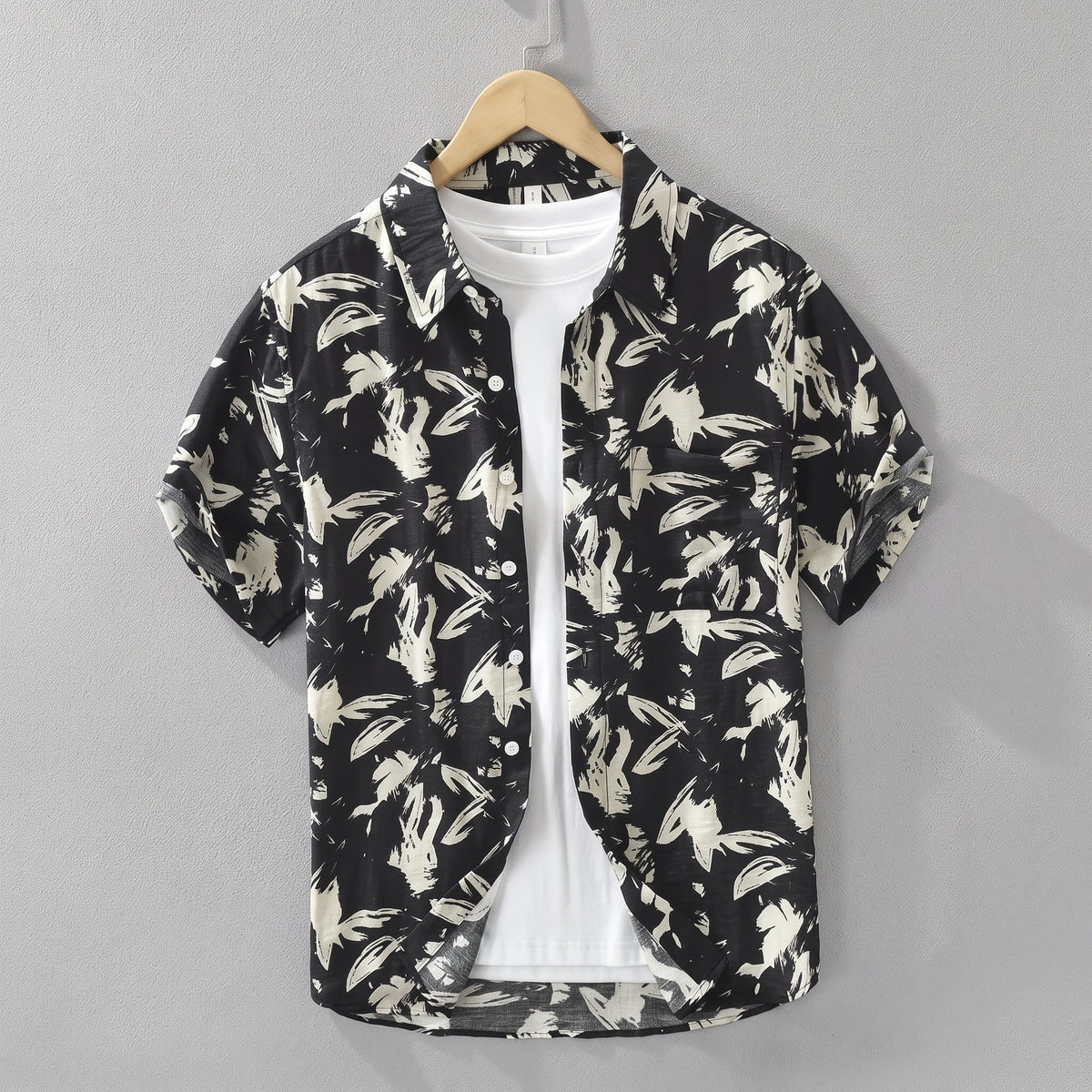 Havlock Men's Button-Up Short Sleeve Shirt hanging over a white top against a grey wall