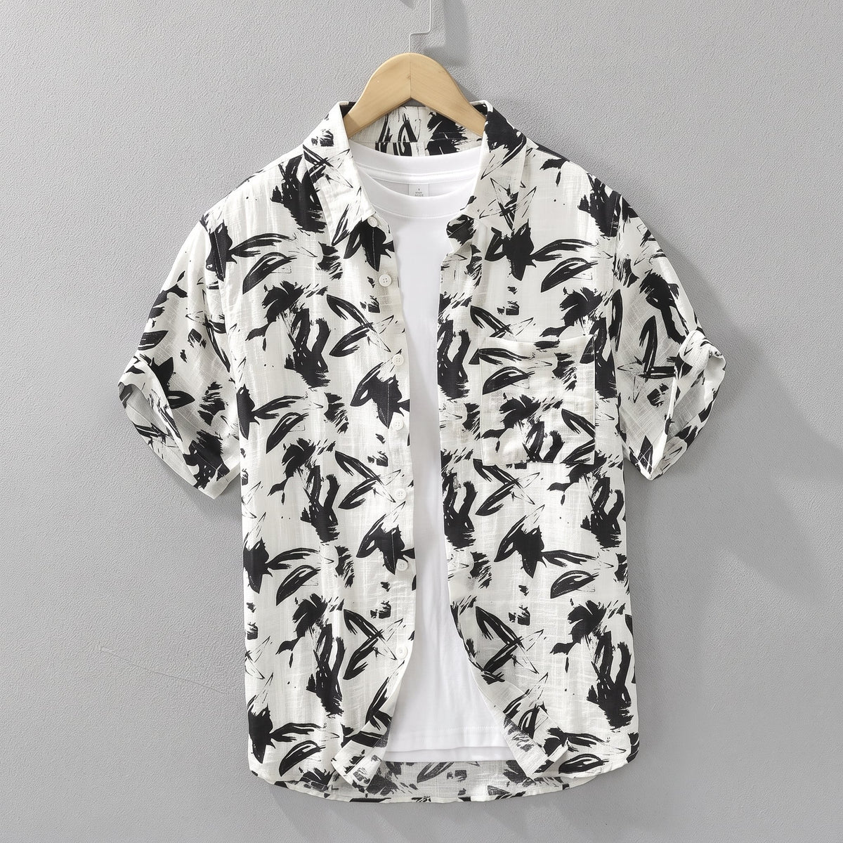 Havlock Men's Button-Up Short Sleeve Shirt in White on a hanger against a grey wall